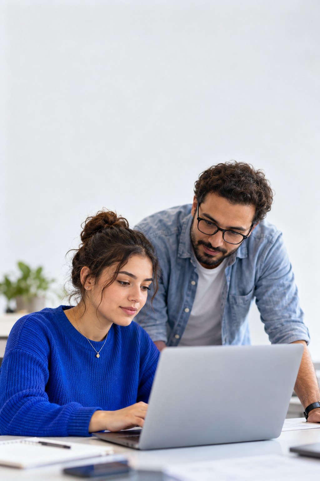 Une apprentie travaille sur un ordinateur portable, accompagnée par son tuteur